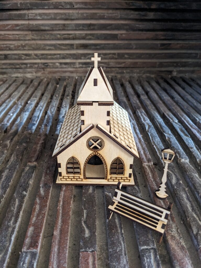 village de noël église vu de face avec un lampadaire et un banc